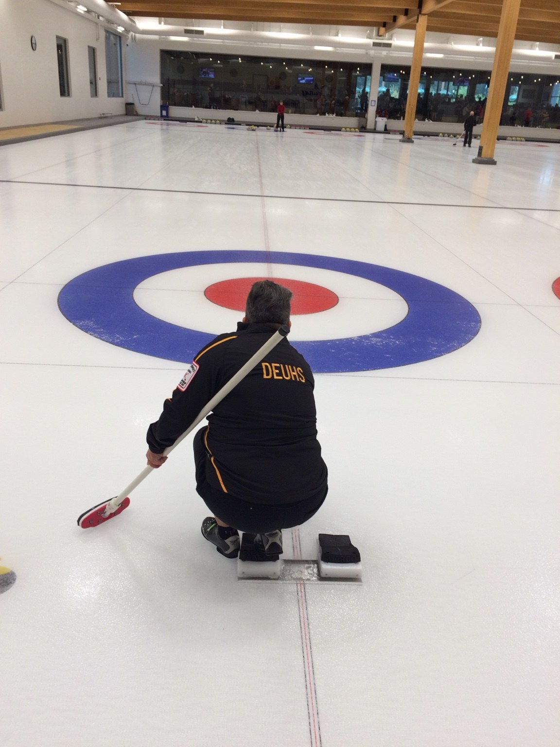 Mary facing down the curling sheet, with Deuhs on her jacket